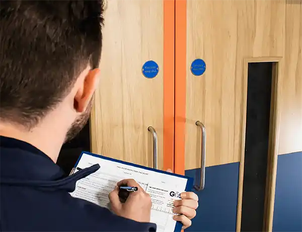 Technician completing a fire door inspection checklist in Newcastle building